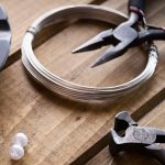 round nose pliers and silver wire with loose beads on a worktop