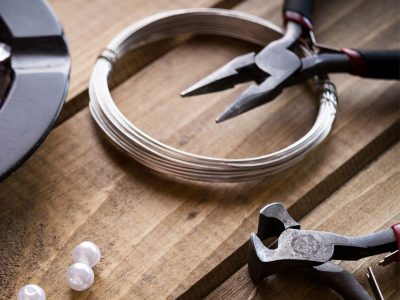 round nose pliers and silver wire with loose beads on a worktop