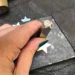 An ImpressArt stamp being used to stamp a design onto a silver star shape