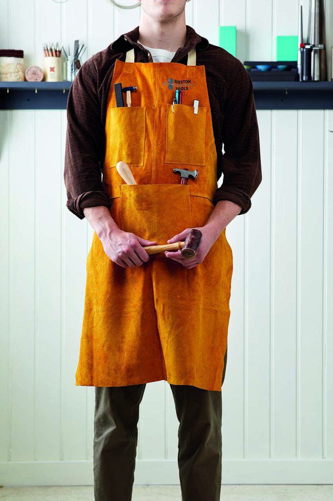 A man wearing an apron, holding a hammer.