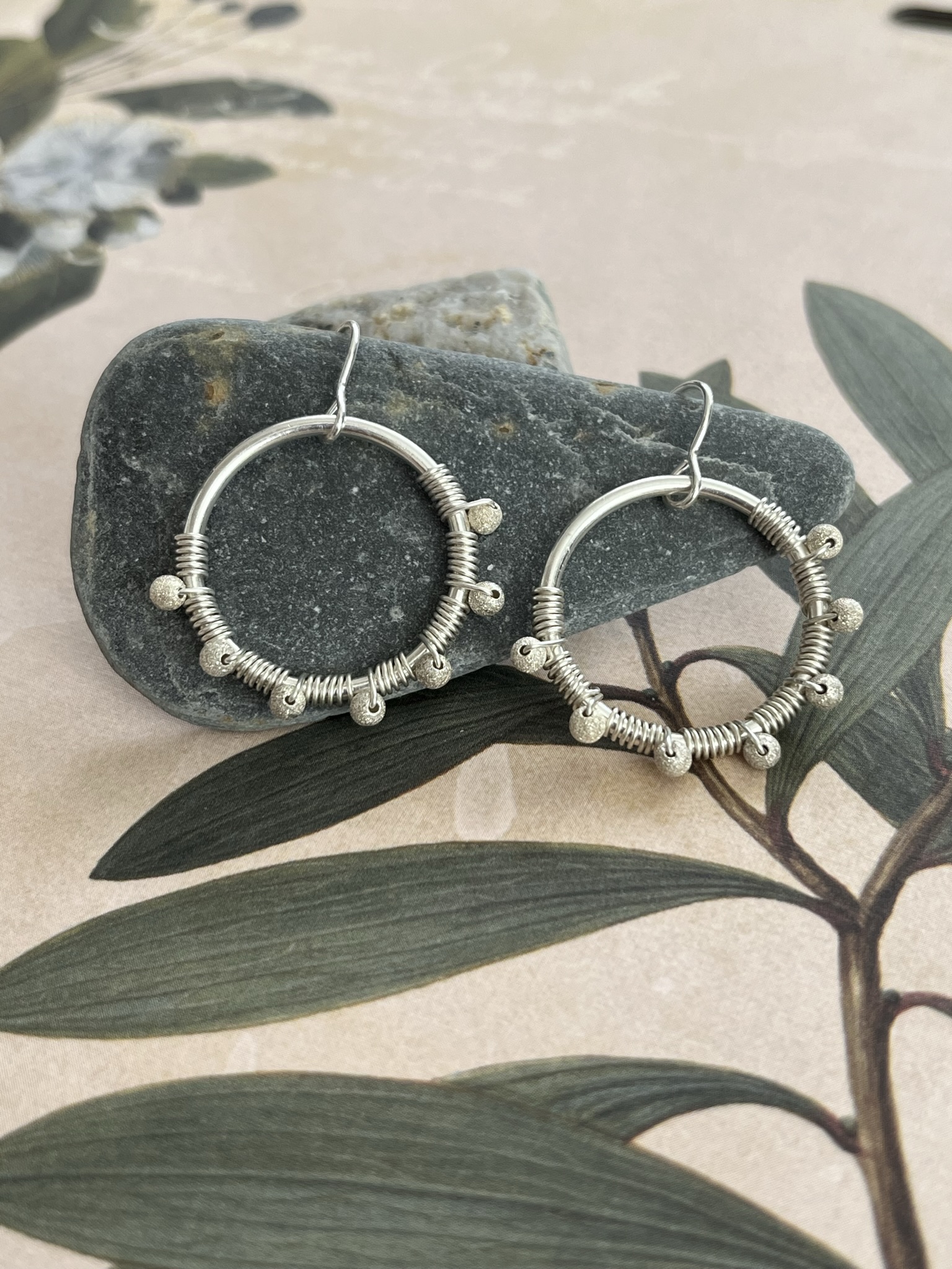 Sterling silver bead wire wrapped hoop earrings on a background