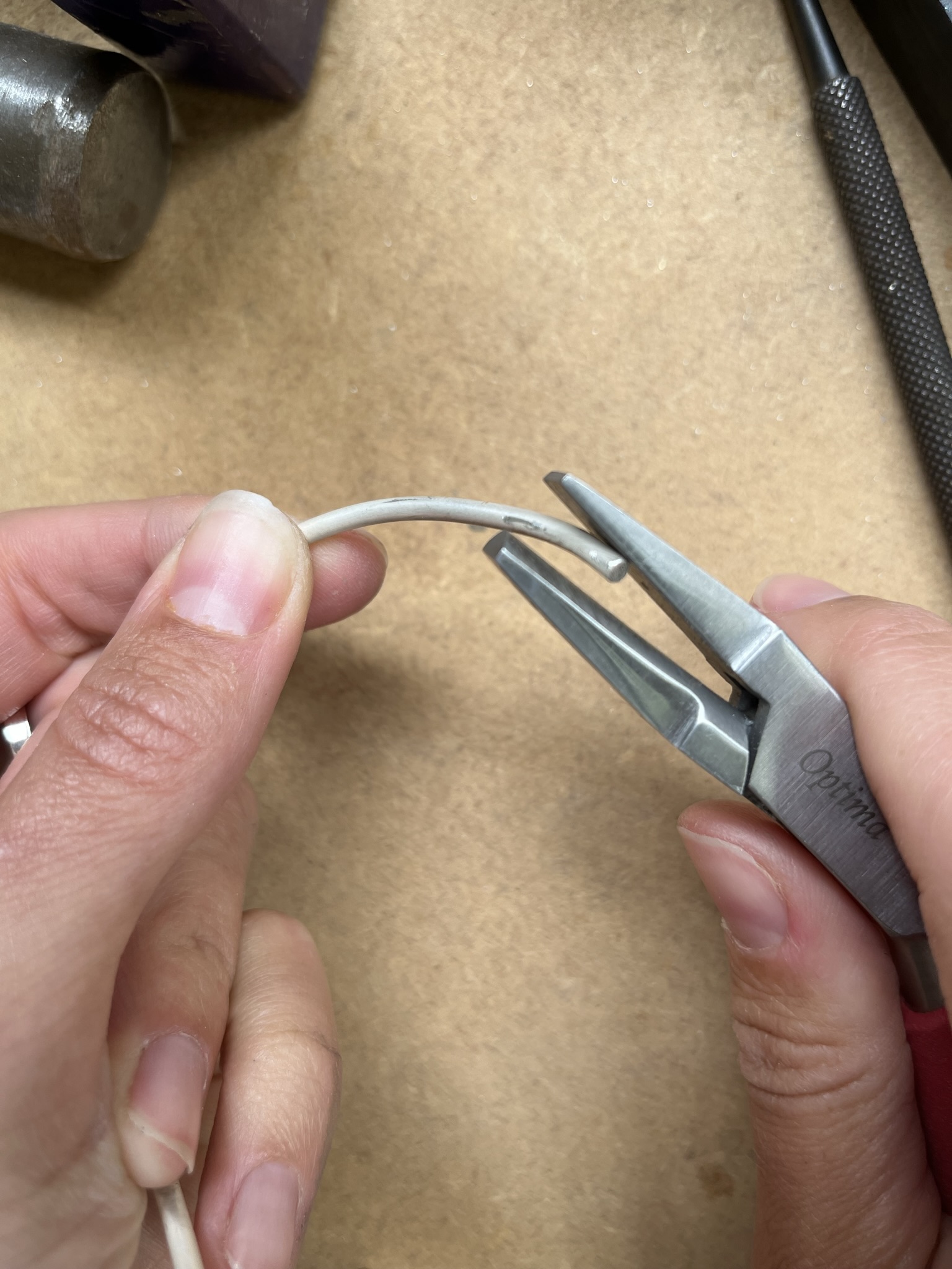 Use half round pliers to bend the wire into a curve.