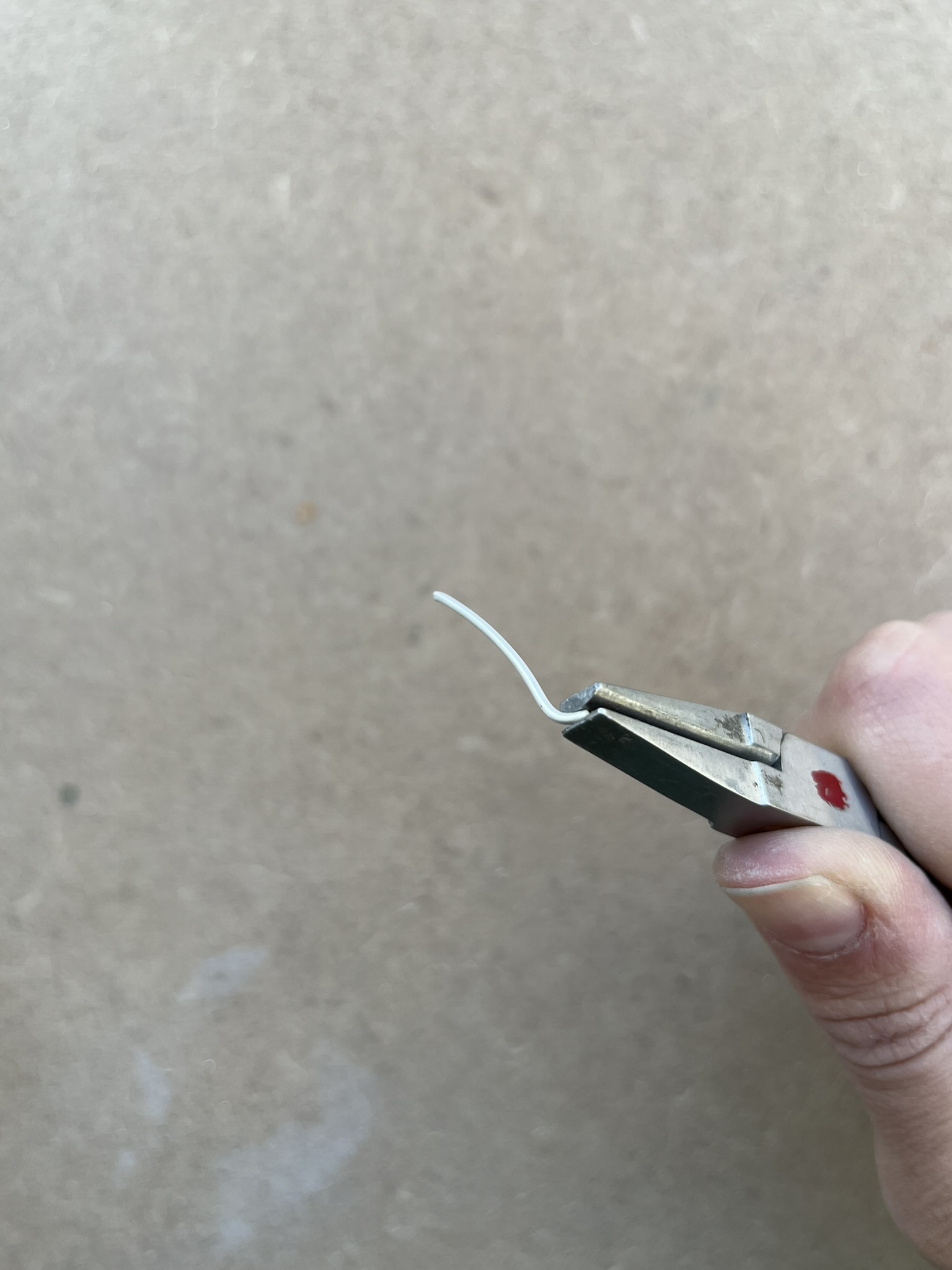 Using tweezers to pick up wire. 