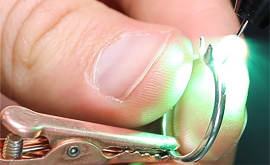 Image alt: fingers holding a ring that is being soldered by an Orion welder